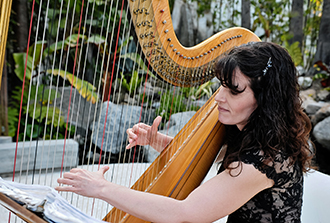 Photo of Pamela Brown performing with her harp at a wedding.